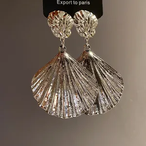 Detailed view of silver metallic pleated seashell drop earrings with textured finish