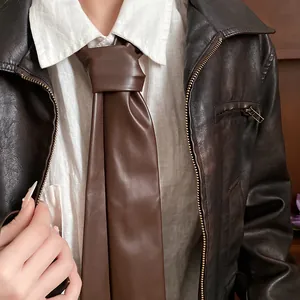 Detailed view of a brown vintage leather necktie styled with a white shirt and jacket