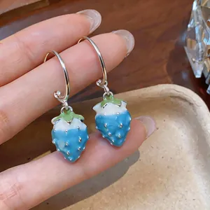 Macro view showing the blue enamel strawberry pendant earrings with silver hooks