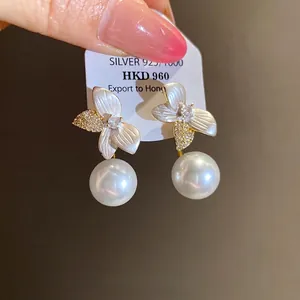 Elegant floral pearl stud earrings with silver needles for a high-end luxury aesthetic.