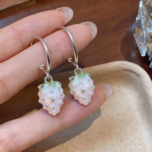 Detailed view of white pearl strawberry drop earrings featuring silver hooks and green leaves