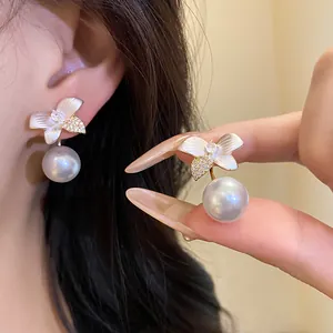 Close-up detail of elegant white flower earrings with large pearls and silver studs