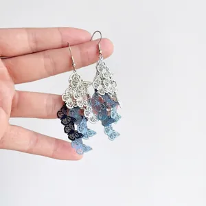 Hand holding layered gradient blue hollow butterfly tassel drop earrings for women