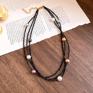 Detailed view of multi-layer black beaded necklace with colorful pearls on vintage book paper