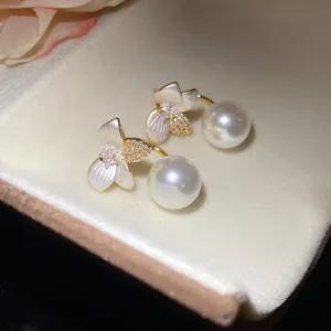 Macro close-up showing detail of floral earrings with white pearls and sparkling crystal accents