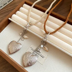 Detail of engraved silver heart locket necklaces with rope cords and shell charms