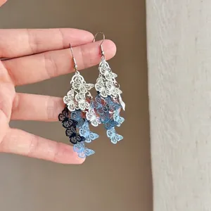 Detailed view of gradient blue filigree butterfly tassel earrings with elegant design