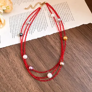 Detailed view of a multi-strand red beaded necklace featuring various colored pearls