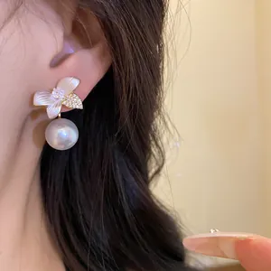 Close-up detail showing an elegant flower-shaped pearl drop earring on model's ear
