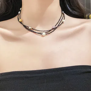 Close-up detail of multi-layer black beaded necklace with colorful pearls on a model