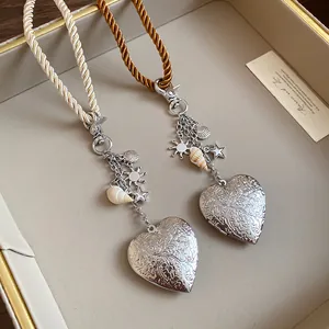 Close-up of engraved heart-shaped locket pendant with delicate shell and star charms