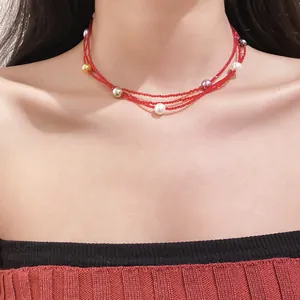 Close-up of model wearing multi-layer red beaded necklace with colorful pearl accents.