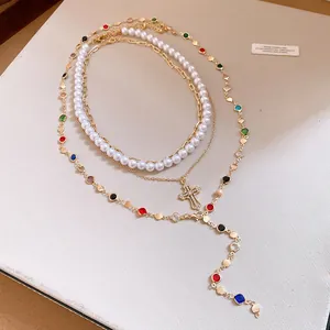 Nahaufnahme einer luxuriösen mehrlagigen Halskette mit Perlen und Diamant-Kreuz