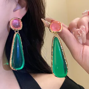 Detailed view of vintage resin teardrop earrings with vibrant pink and green stones in gold