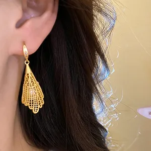 Elegant gold hollow lace earrings with zircon and pearl drop shown on model's ear