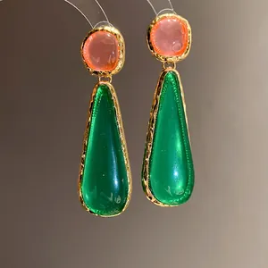 Detailed macro view of vintage resin water-drop earrings with pink and green pendants