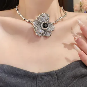 Gros plan d'un collier choker fleur en strass argenté avec une pierre centrale noire.