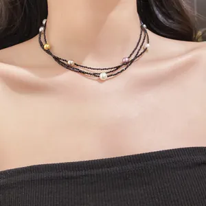 Detail shot of an elegant multi-layered black bead necklace with scattered colorful pearls