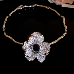 Gros plan d'un collier ras du cou en strass avec une fleur et une pierre noire centrale