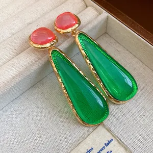 Detail view of vintage-style red and green resin water drop earrings in a jewelry box