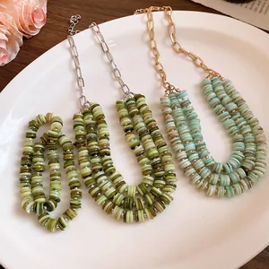 Macro view of multi-layered shell beaded necklaces in green and teal on a white plate