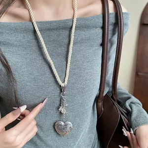 Detail view of heart locket pendant with rope chain and shell charms