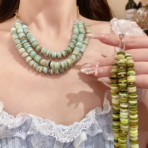 Detailed view of green multi-layer shell bead necklace on a model for vacation style