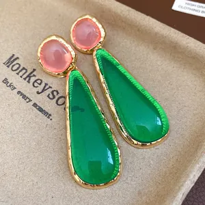 Detailed macro view of vintage resin drop earrings featuring emerald green teardrops