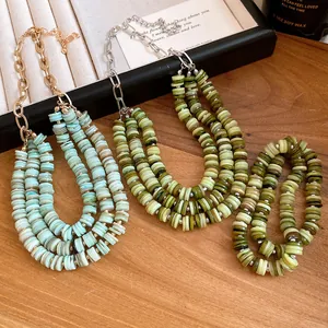 Detail of multilayer shell bead necklaces in turquoise and olive green on a wooden tray