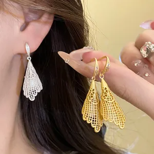 Close-up view of elegant hollow lace dangle earrings with zircon in gold and silver