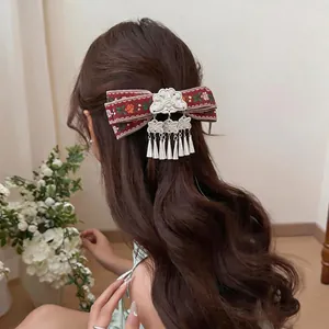 Vintage Bohemian ribbon bow hair clip with silver tassels worn on wavy long hair