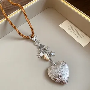 Detailed macro shot of vintage silver engraved heart locket necklace with sea charms