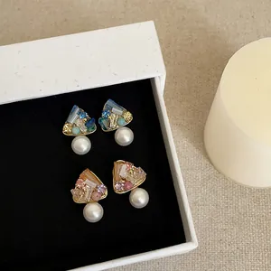 Κοντινό πλάνο με κομψά σκουλαρίκια με ζιργκόν και πέρλες, επιχρυσωμένα με 18 καράτια