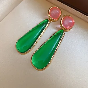 Detailed close-up of vintage style teardrop earrings with green resin and pink accents