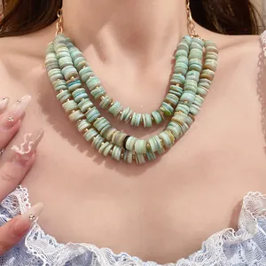 Close-up of multi-layer mint green shell bead necklace with gold accents