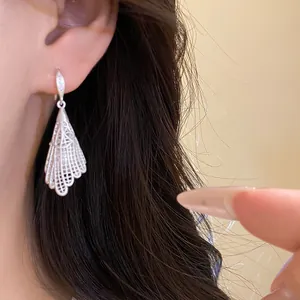 Close-up of elegant silver openwork lace pendant earring worn on ear with dark hair