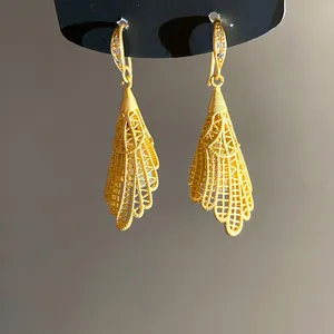 Macro detail of golden hollow lace fan-shaped drop earrings with zircon accents