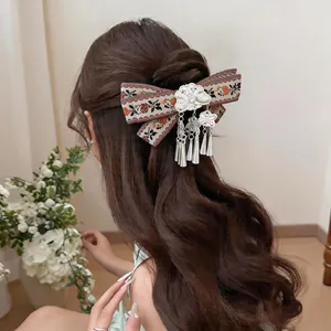 Close-up of retro Bohemian woven ribbon hair clip with metallic floral tassels