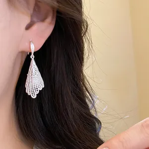 Detailed macro view of elegant silver zircon hollow lace drop earring on model ear