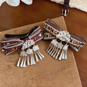 Detailed view of vintage Bohemian hair clips with ethnic ribbon and silver tassel charms
