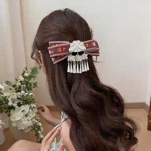 Detailed view of bohemian red ribbon hair clip with silver tassels on wavy hair