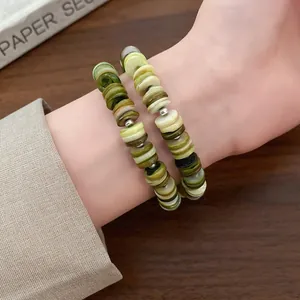 Detailed close-up of a multi-layer shell beaded bracelet in green and beige tones