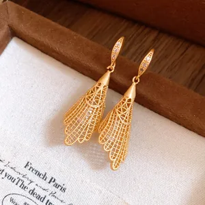 Detailed close-up of golden hollow lace drop earrings with zircon embellishments