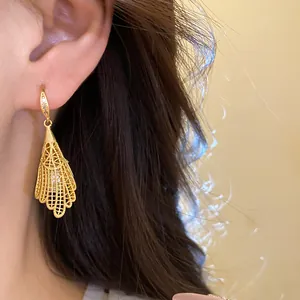 Detailed close-up of refined golden hollow lace drop earrings with pearl and zircon accents