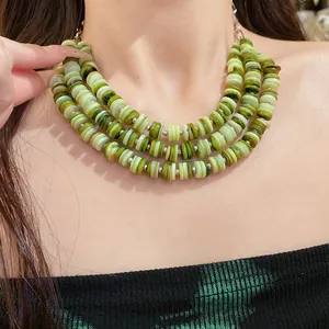 Close-up detail of a vibrant multi-layered shell beaded necklace in fresh green tones