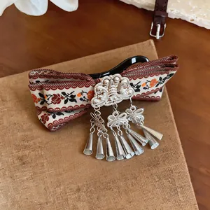 Detailed macro view of vintage Bohemian hair clip featuring floral ribbon and metal tassels