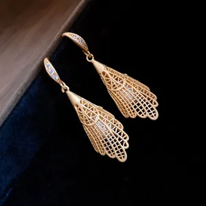Detailed close-up showing golden hollow lace drop earrings with pearl inlays and zircons