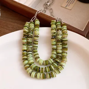 Detailed view of a triple-layered green shell heishi bead necklace with silver chain