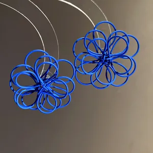 Detail view of blue spray-painted wire-woven flower stud earrings with hollow design