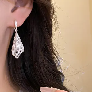 Detail view of elegant silver-colored hollow lace drop earrings with zircon accents on model